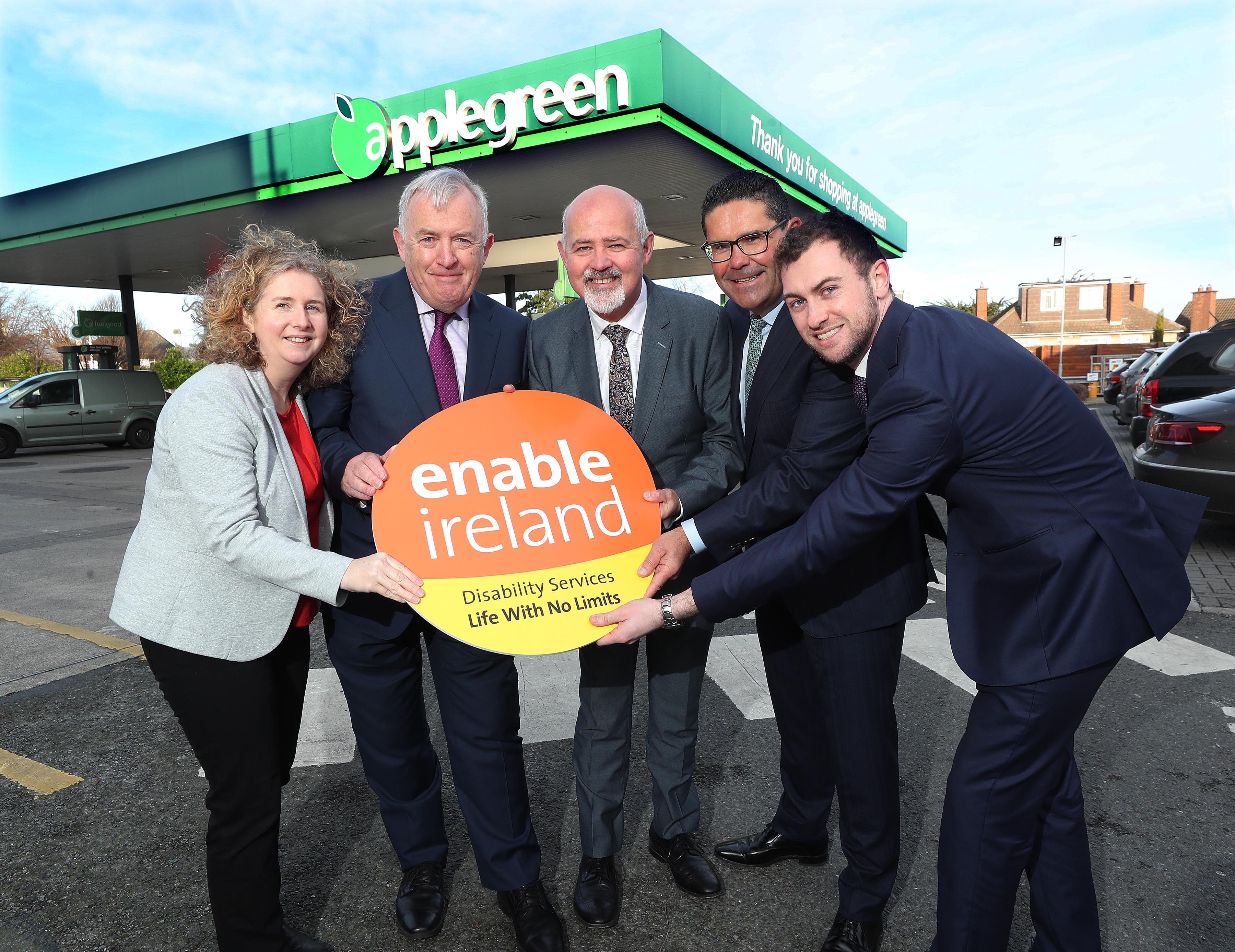 Woman and four men holding an Enable Ireland logo at an Applegreen petrol station