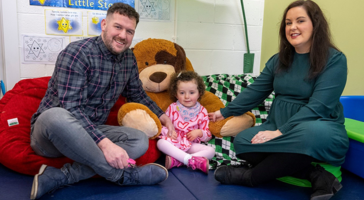 Mum and Dad sitting in soft play area with toddler daughter