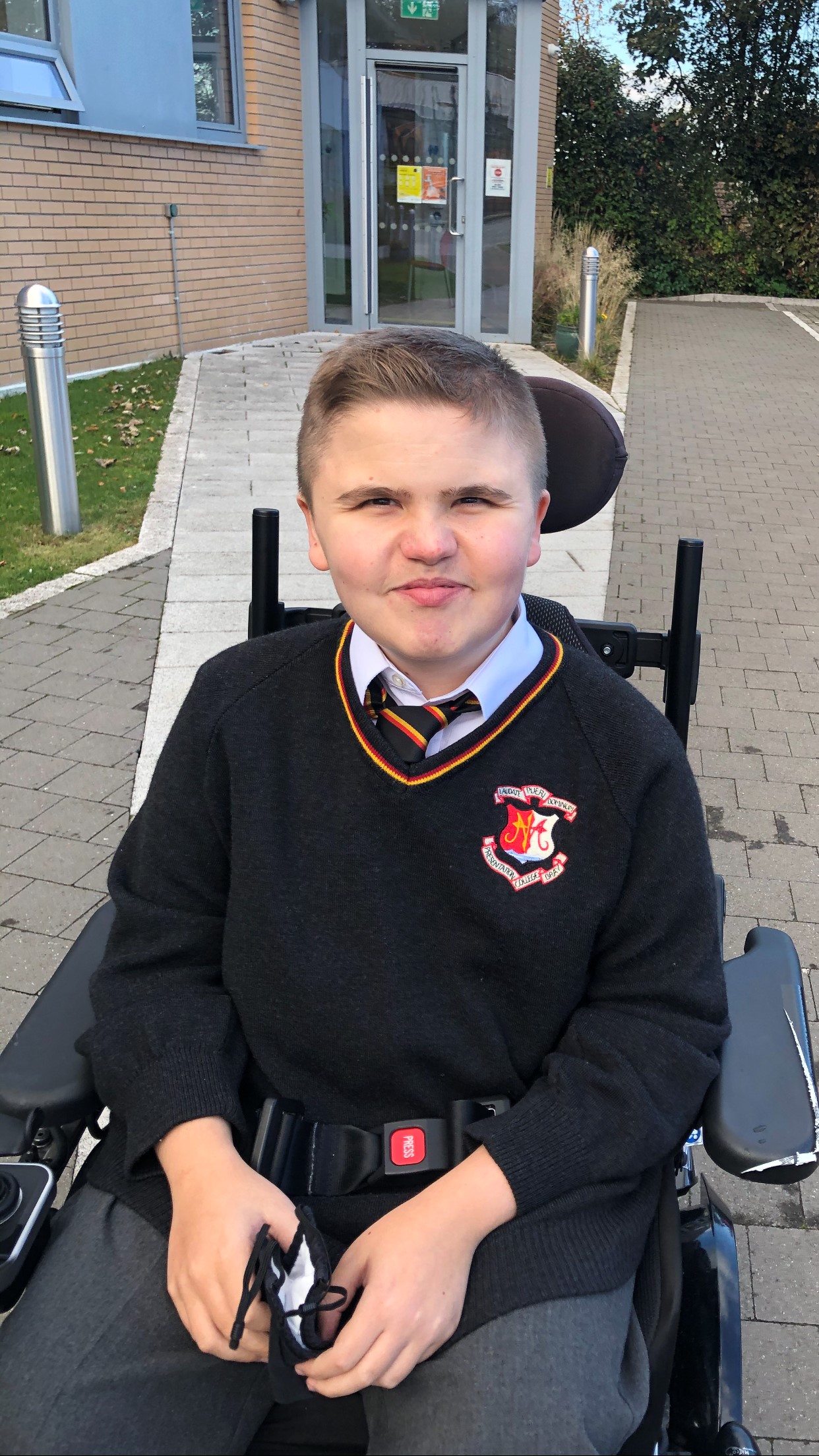 Boy wearing school uniform in wheelchair