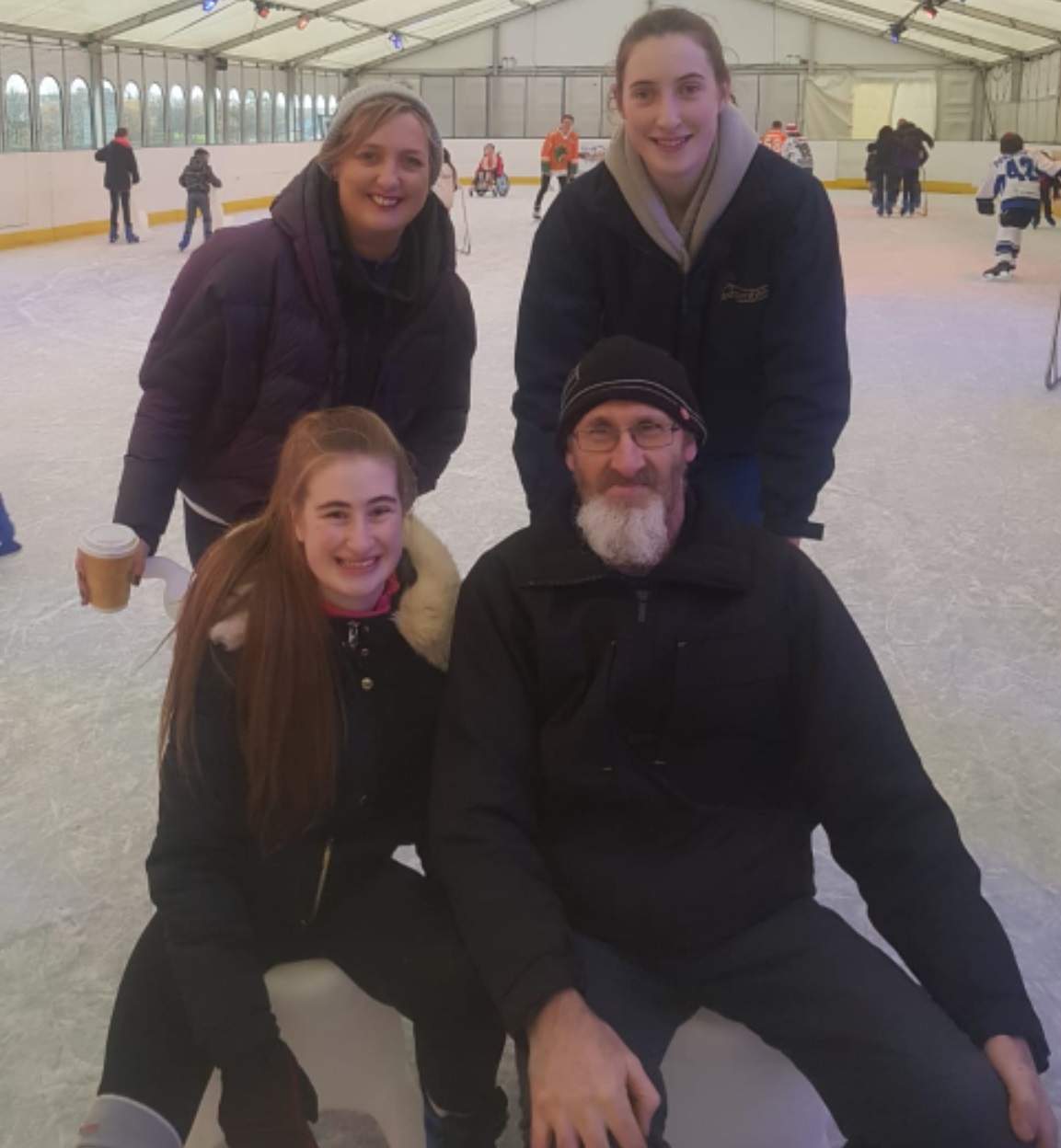 A man and a woman seated with two women standing behind at an Ice Rink