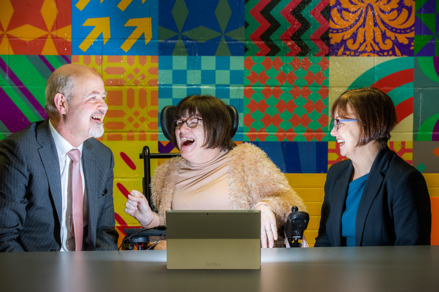 Man and two woman, one is a wheelchair user, chatting and laughing 