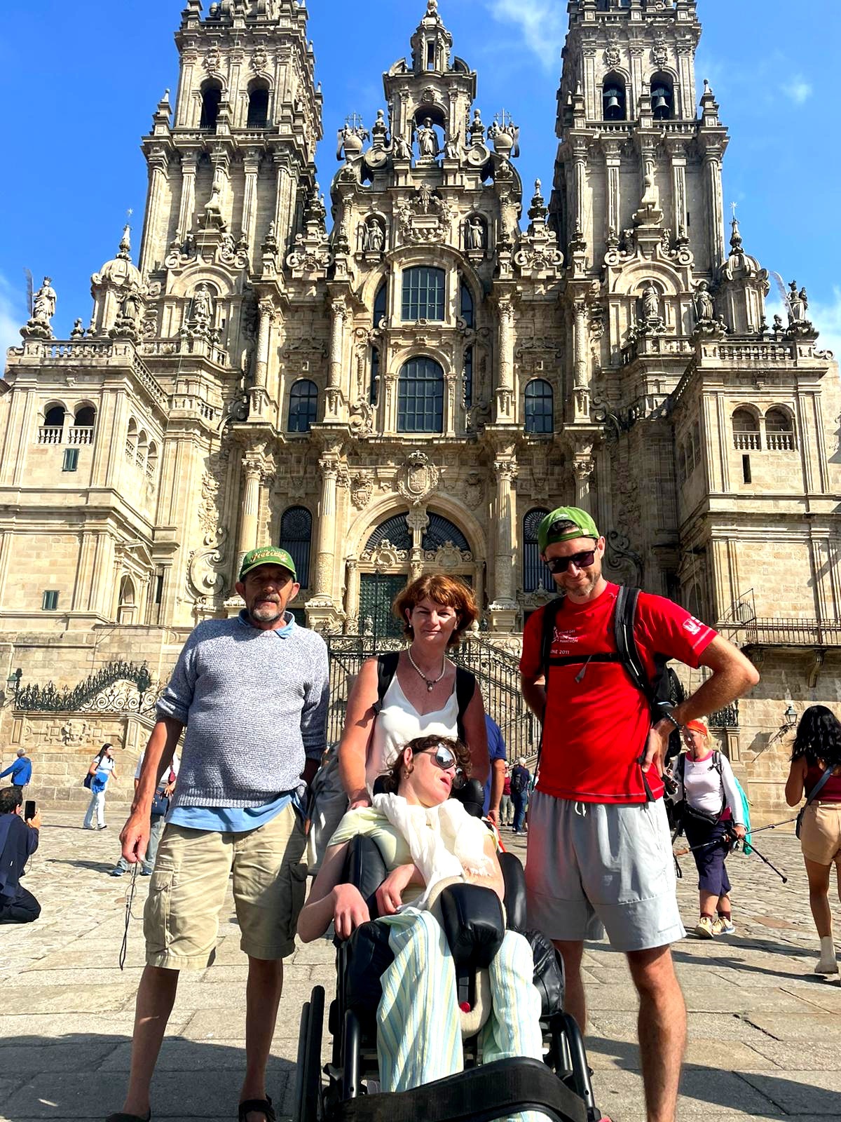 Four people, including one wheelchair user, pose in front of a cathedral