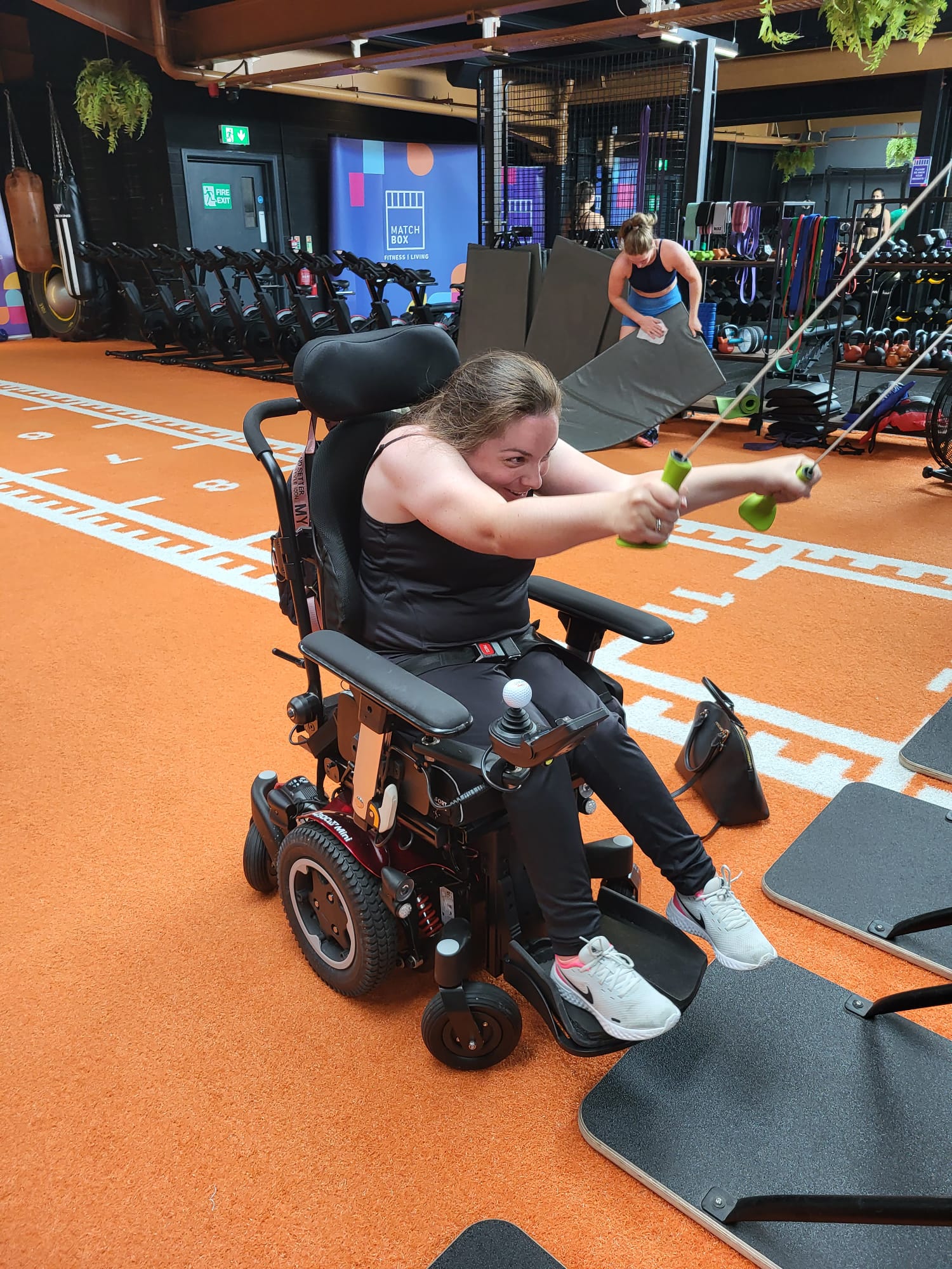 A photo of a young woman using a wheelchair and exercising in the gym