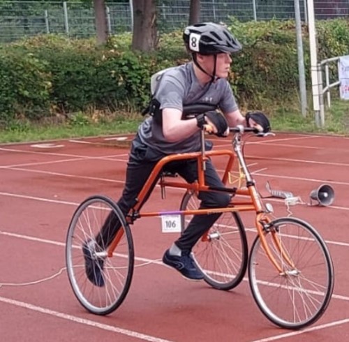 A teenage boy using a frame runner bike on an athletics track.