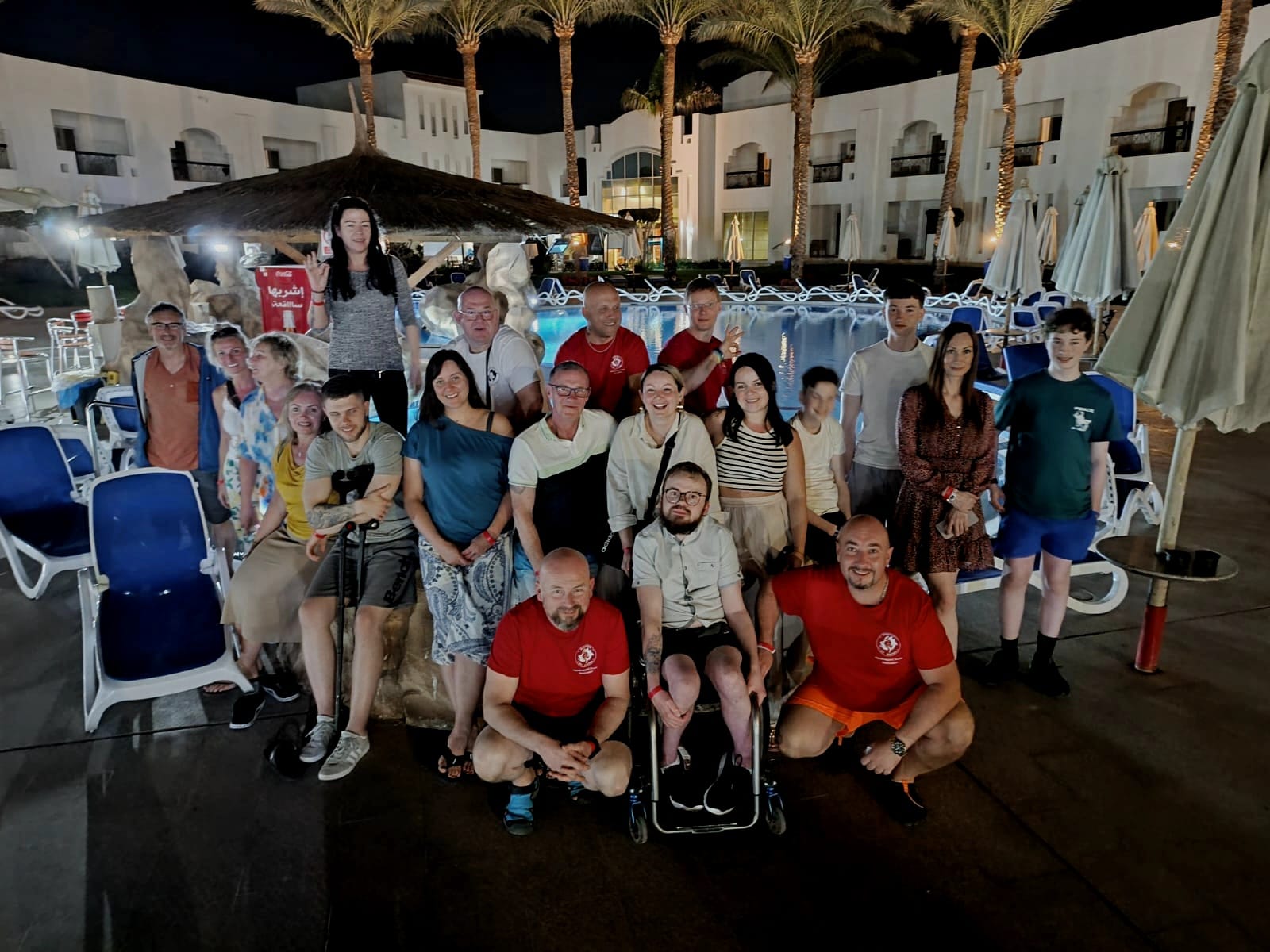 A group of people posed for a photo in front of a swimming pool.