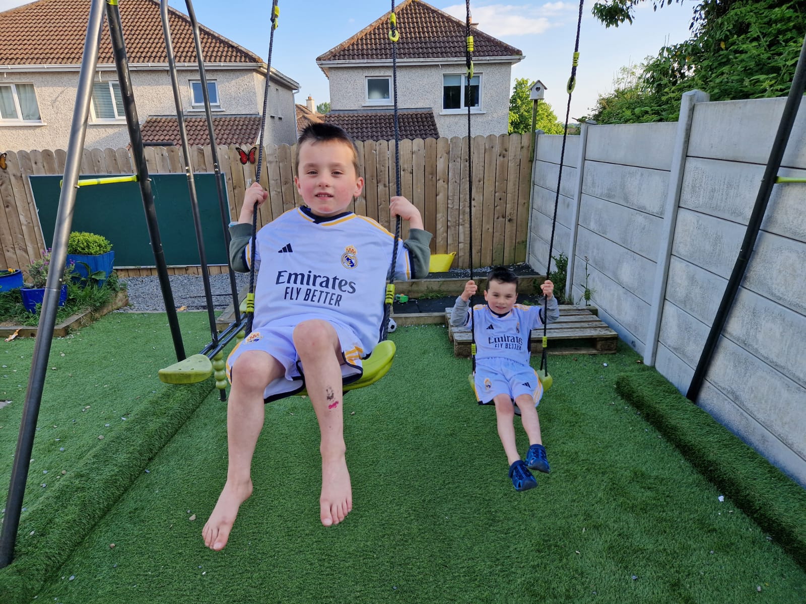 Two young boys wearing football jerseys on swings