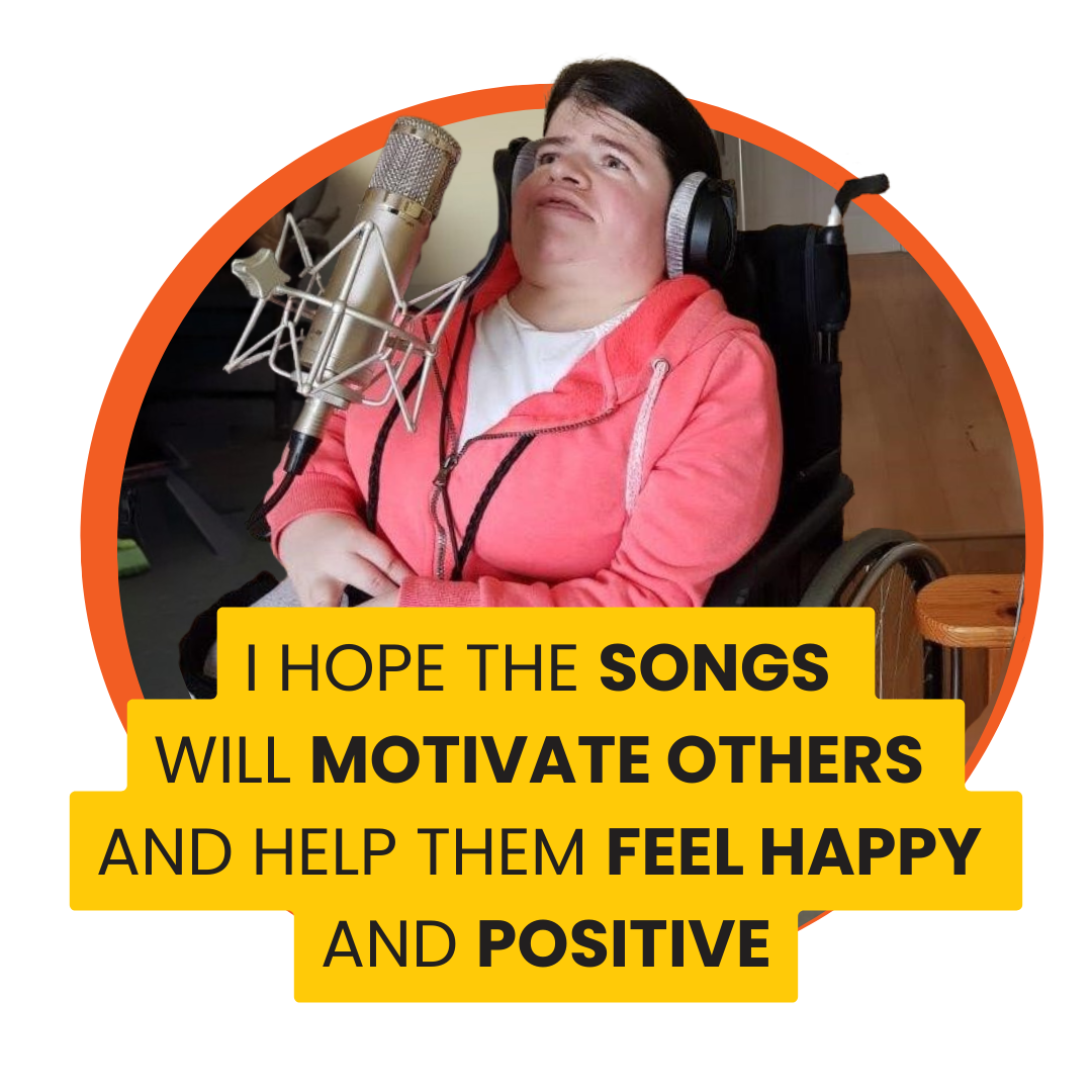 Person in a wheelchair wearing a coral hoodie and headphones, speaking into a professional microphone in a recording setup. A quote says "I hope the songs will motivate others and help them feel happy and positive"