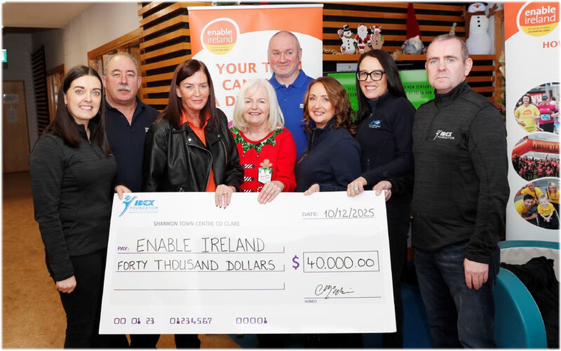 Group holding a large cheque for $40,000 presented to Enable Ireland, standing indoors in front of Enable Ireland banners and display boards.