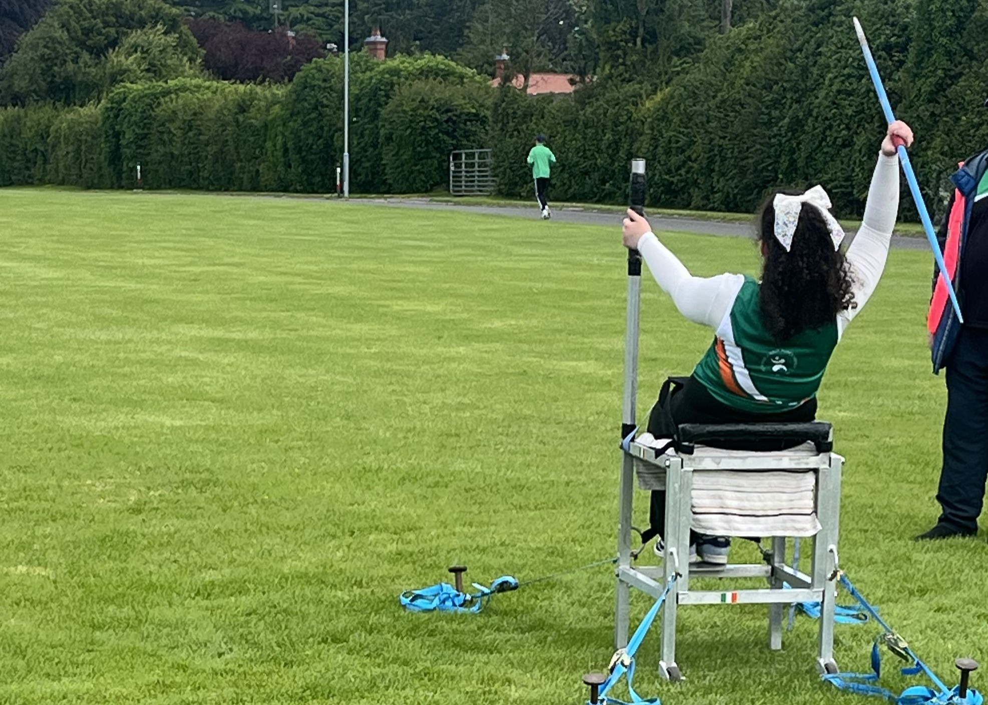 Life With No Limits Champion Maisie Randle competing in a seated javelin event, preparing to throw on a grass athletics field.