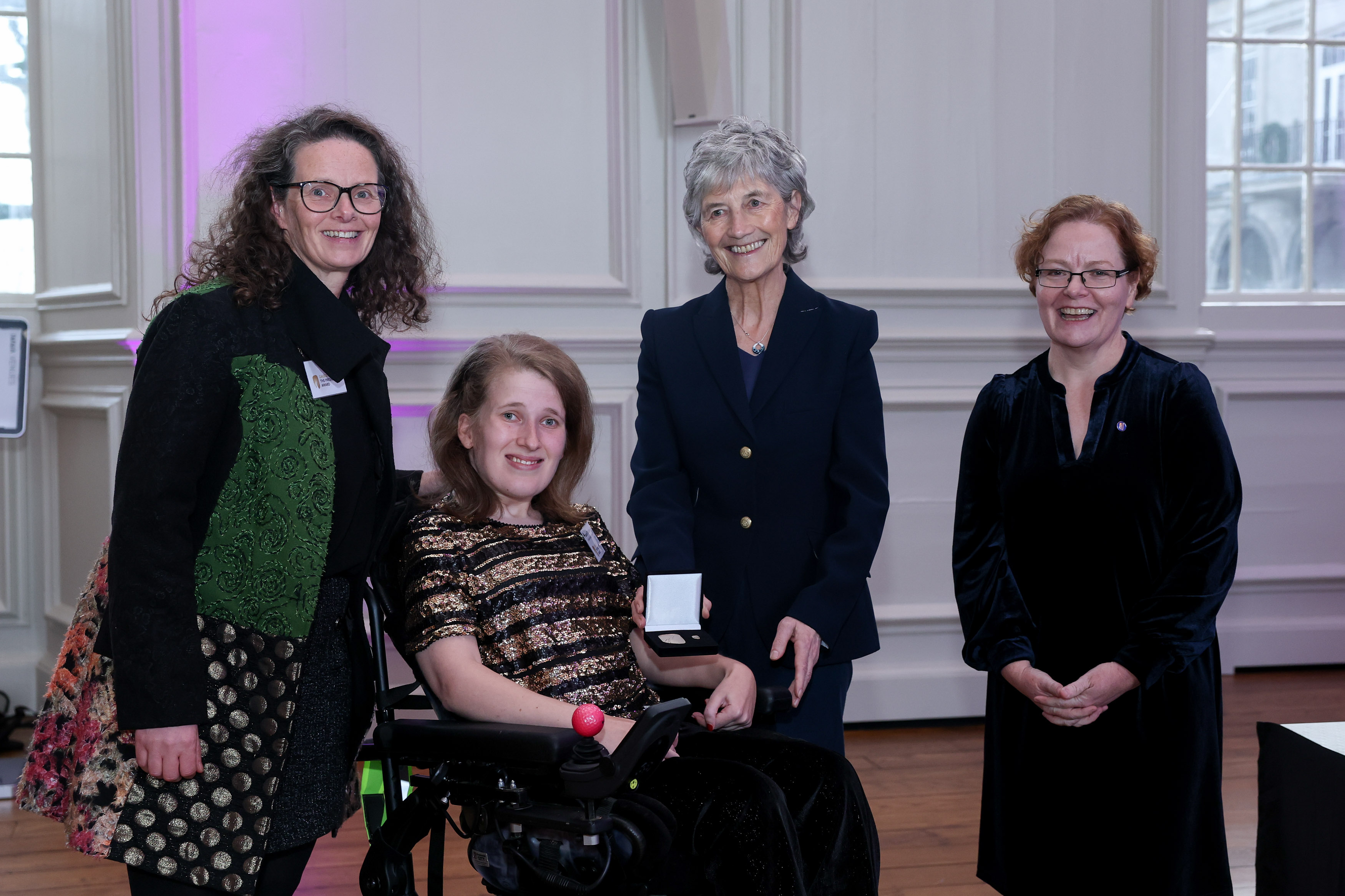 Life With No Limits Champion Sarah O’Sullivan receiving a President’s Award at a formal ceremony, seated in a wheelchair and holding an award medal alongside guests at the presentation.