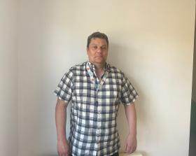 Man in a check shirt standing against a white background