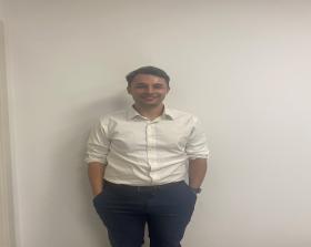 A man in a white shirt stands against a white wall