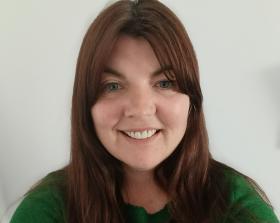 Woman with long brown hear wearing a green jumper