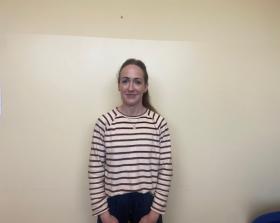 Woman in a striped long sleeve top standing against a white wall