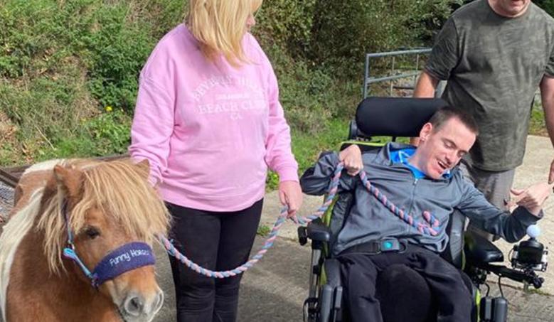 Wheelchair user and woman with a pony and a dog