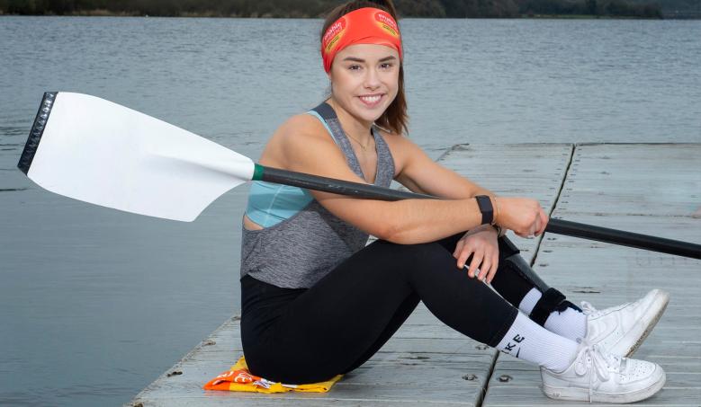 woman beside water holding an oar